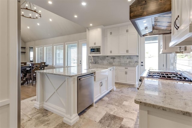 kitchen featuring decorative backsplash, appliances with stainless steel finishes, a kitchen island with sink, white cabinetry, and lofted ceiling