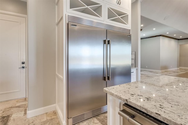 kitchen with crown molding, light stone countertops, white cabinetry, and stainless steel appliances