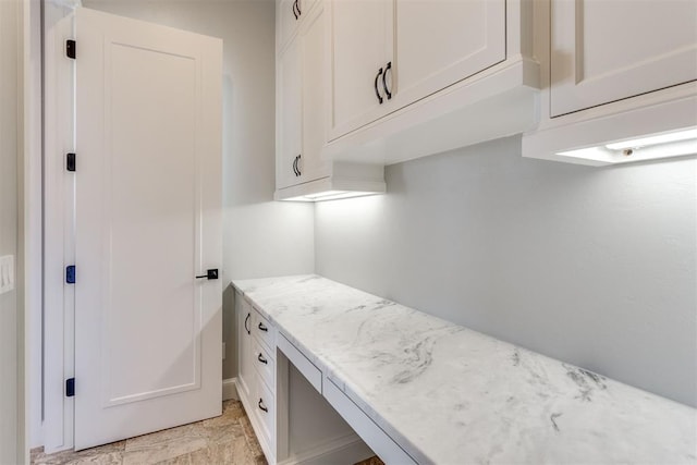 interior space with white cabinetry and light stone countertops