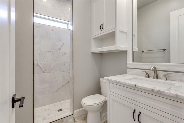 bathroom with a tile shower, vanity, and toilet