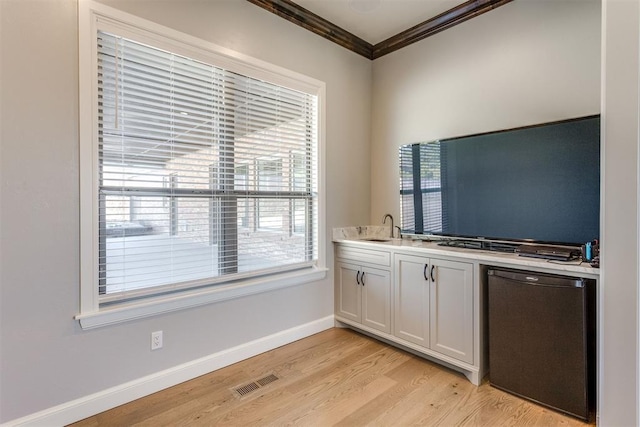 kitchen with white cabinets, plenty of natural light, refrigerator, and ornamental molding