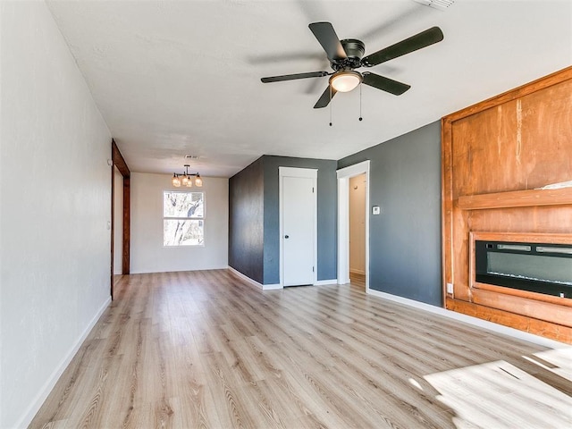 unfurnished living room featuring light hardwood / wood-style flooring and ceiling fan with notable chandelier