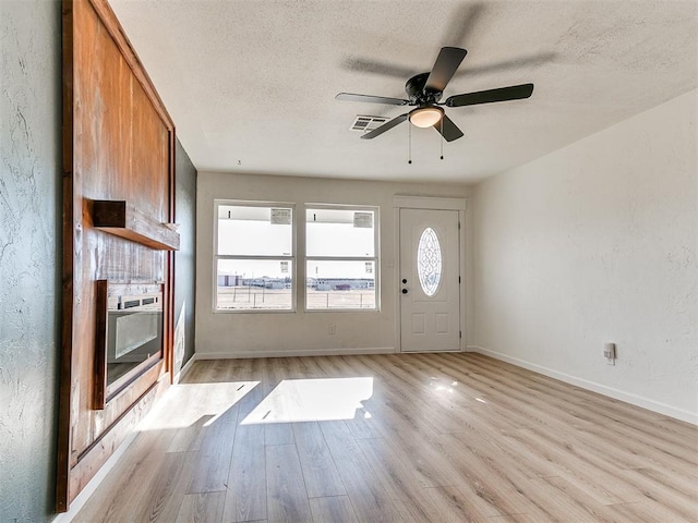 foyer featuring a textured ceiling, light wood-type flooring, and ceiling fan