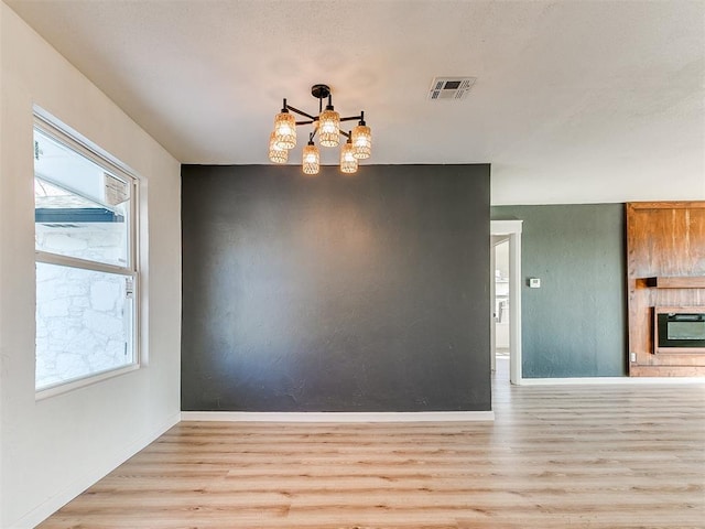 unfurnished dining area featuring an inviting chandelier, heating unit, and light hardwood / wood-style flooring