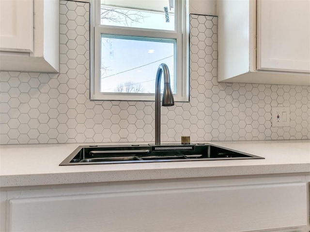 details featuring sink, white cabinets, light stone countertops, and tasteful backsplash