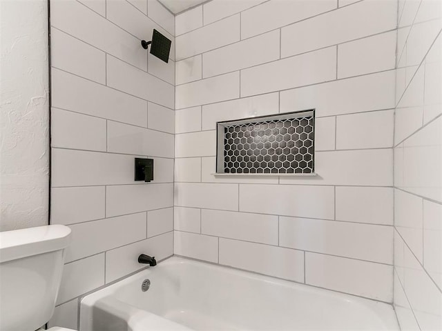 bathroom featuring tiled shower / bath and toilet