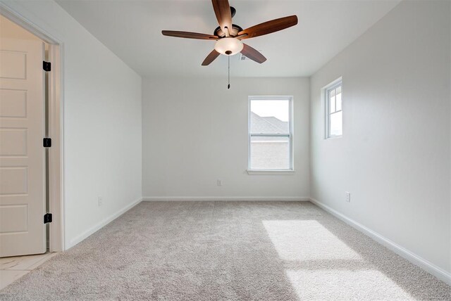 empty room featuring light carpet, baseboards, and a ceiling fan