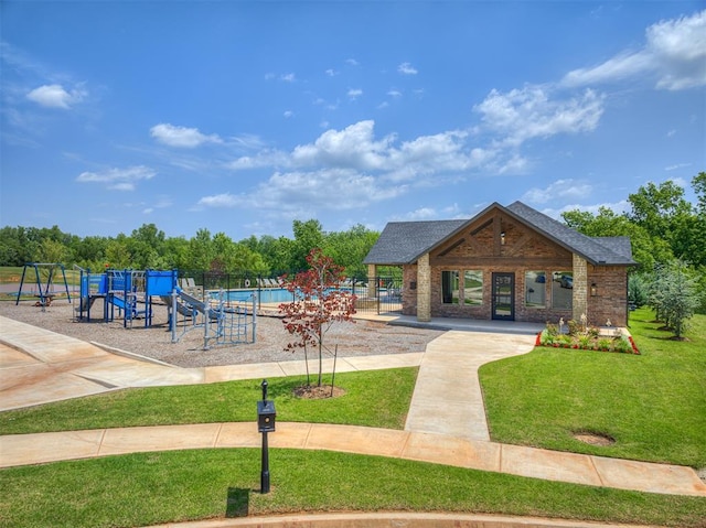 view of property's community featuring a lawn, fence, and playground community