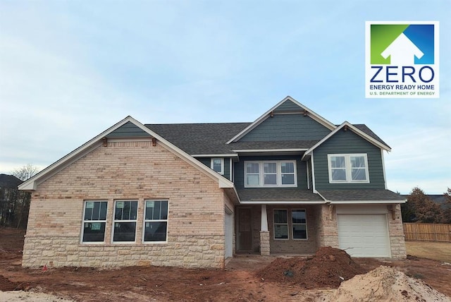 craftsman house with an attached garage, a shingled roof, and brick siding