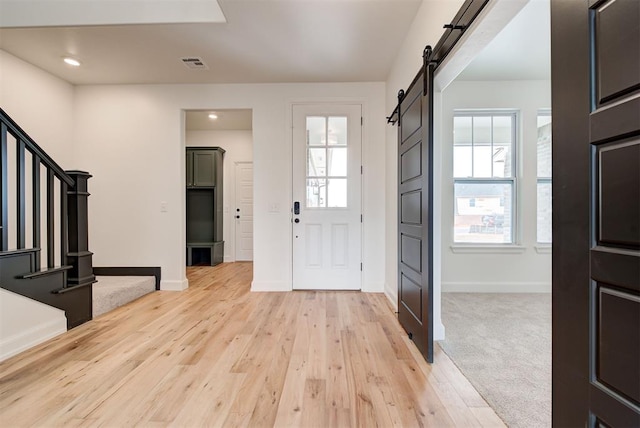 entryway featuring visible vents, plenty of natural light, stairway, and a barn door