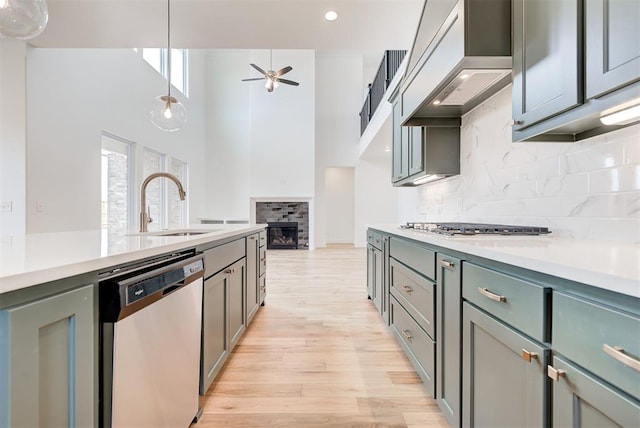 kitchen featuring custom range hood, hanging light fixtures, stainless steel appliances, light countertops, and a fireplace