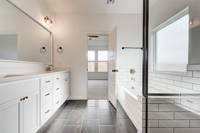 bathroom with tile patterned flooring, double vanity, a sink, and a bath