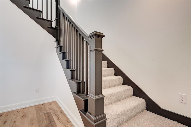 stairway with wood finished floors and baseboards