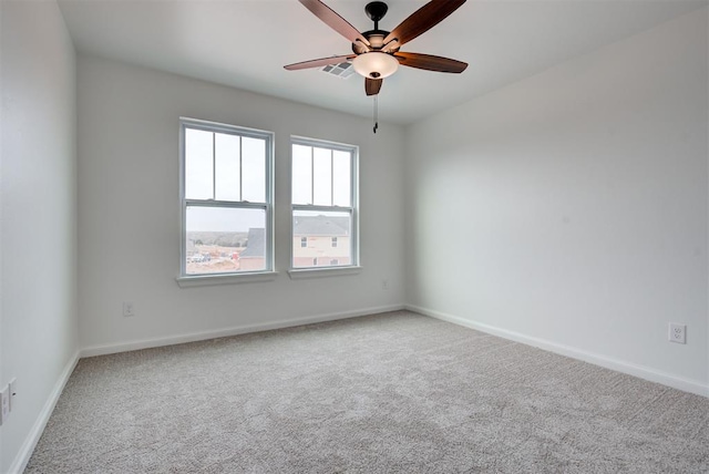 carpeted spare room with ceiling fan, visible vents, and baseboards