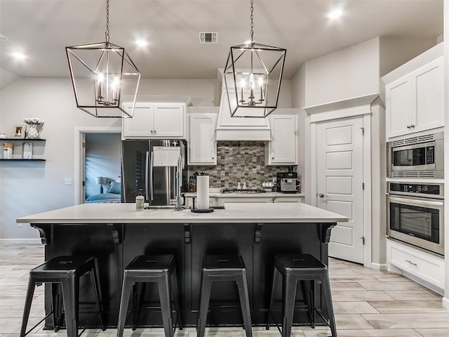 kitchen featuring a center island with sink, pendant lighting, white cabinetry, and stainless steel appliances