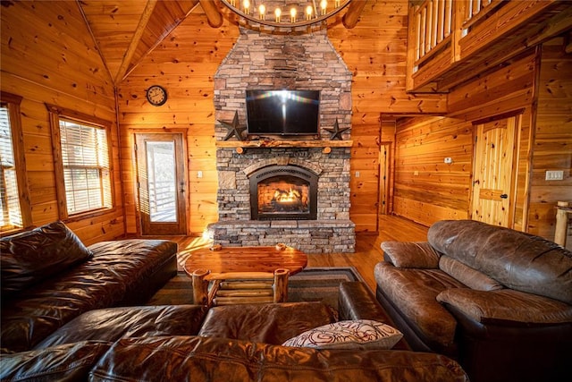 living room featuring wood walls, high vaulted ceiling, an inviting chandelier, a fireplace, and wood ceiling