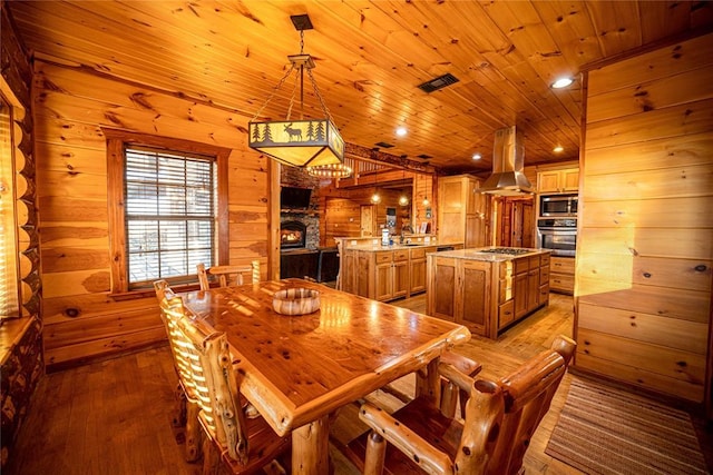 dining space with lofted ceiling, wooden ceiling, wooden walls, light hardwood / wood-style flooring, and a fireplace