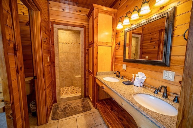 bathroom with tile patterned floors, wooden walls, vanity, and tiled shower