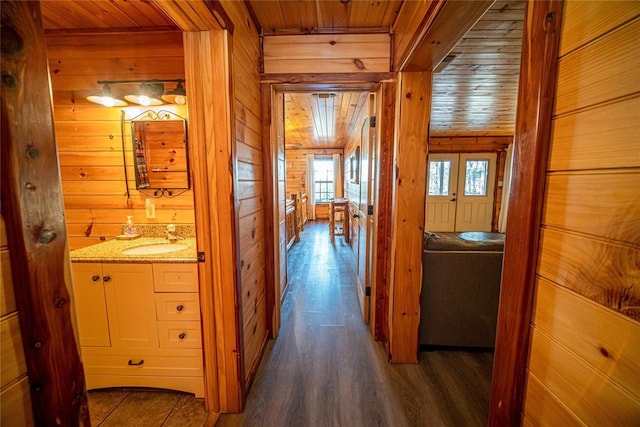 hall featuring wooden ceiling, sink, wooden walls, and dark wood-type flooring