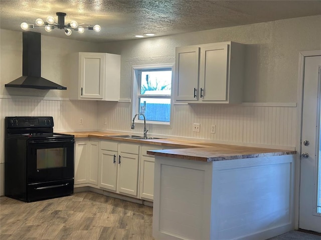 kitchen with electric range, wall chimney exhaust hood, butcher block countertops, light hardwood / wood-style floors, and white cabinetry