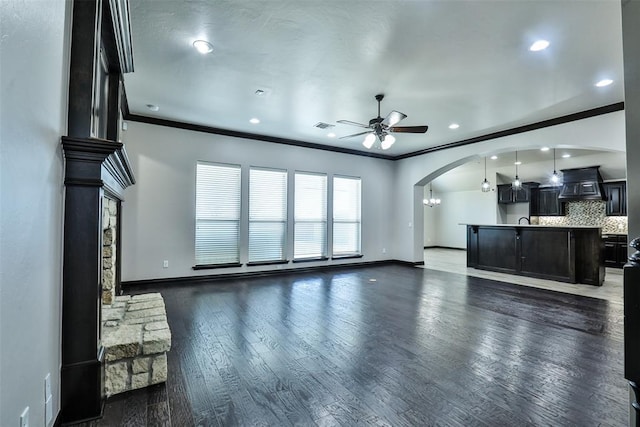 unfurnished living room featuring ceiling fan, crown molding, and dark hardwood / wood-style floors