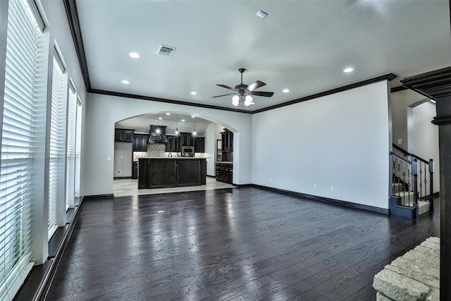 unfurnished living room featuring ceiling fan, crown molding, and dark wood-type flooring