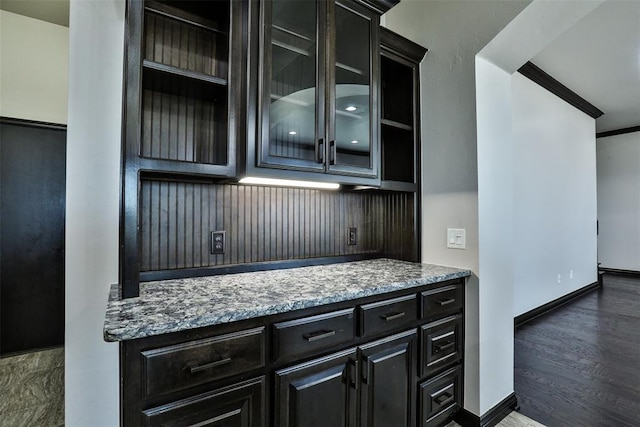 bar featuring dark hardwood / wood-style floors, light stone countertops, and ornamental molding