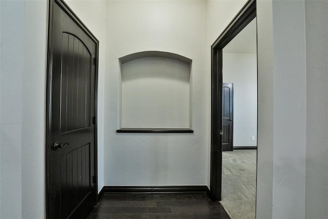 hallway featuring dark colored carpet