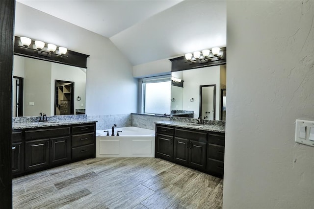 bathroom with a tub, vanity, and lofted ceiling