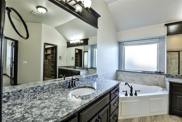 bathroom with a washtub, lofted ceiling, and vanity