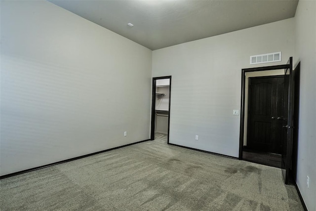 unfurnished bedroom featuring a spacious closet, light carpet, and a closet