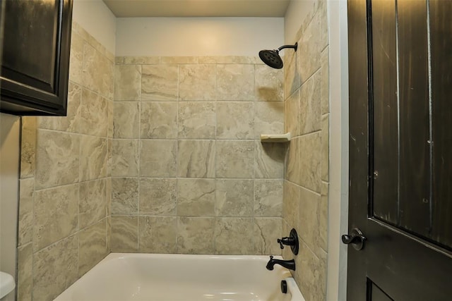 bathroom with toilet and tiled shower / bath