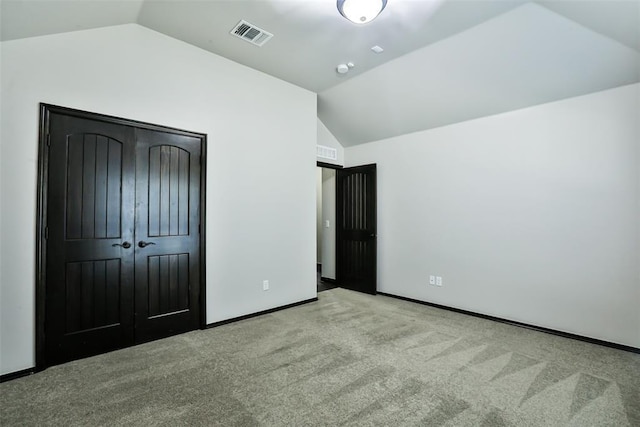 unfurnished bedroom with light carpet, a closet, and lofted ceiling