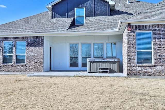 back of house featuring a patio, a hot tub, and a lawn