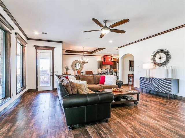 living room featuring a tray ceiling, dark hardwood / wood-style flooring, ceiling fan with notable chandelier, and ornamental molding