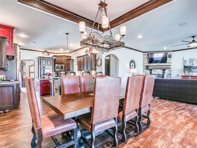 dining area with a fireplace, light hardwood / wood-style flooring, ceiling fan, and ornamental molding