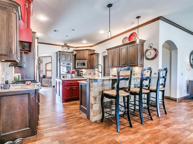 kitchen with light stone countertops, backsplash, a center island with sink, and stainless steel appliances