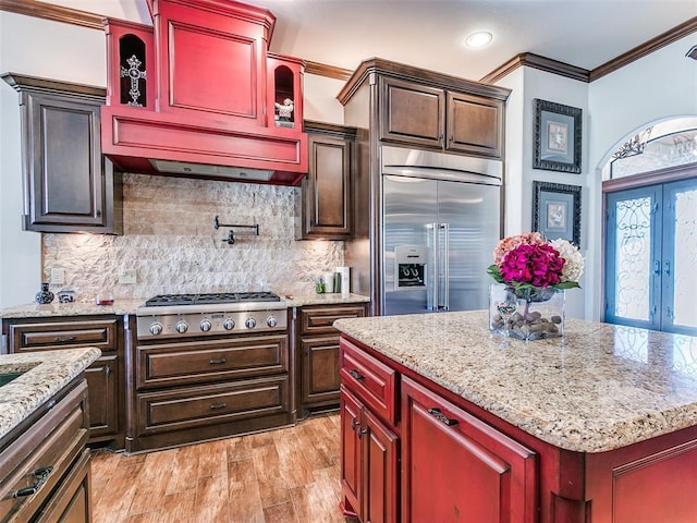 kitchen with a center island, backsplash, ornamental molding, light hardwood / wood-style floors, and stainless steel appliances