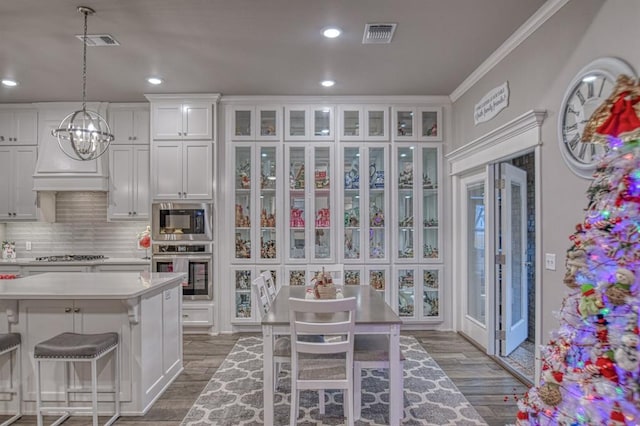 kitchen with decorative backsplash, white cabinets, hardwood / wood-style flooring, and appliances with stainless steel finishes