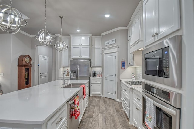 kitchen featuring decorative backsplash, an island with sink, stainless steel appliances, and a notable chandelier