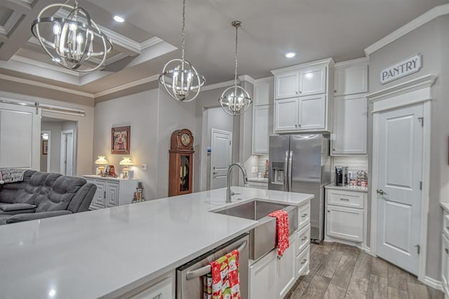 kitchen with a barn door, white cabinetry, stainless steel appliances, and ornamental molding