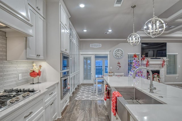 kitchen featuring white cabinets, a notable chandelier, stainless steel appliances, and decorative light fixtures