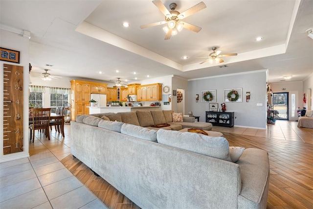 living room with ceiling fan, a healthy amount of sunlight, light wood-type flooring, and a tray ceiling