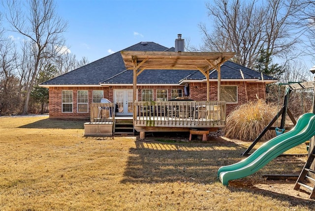 back of house featuring a playground, a wooden deck, a lawn, and french doors