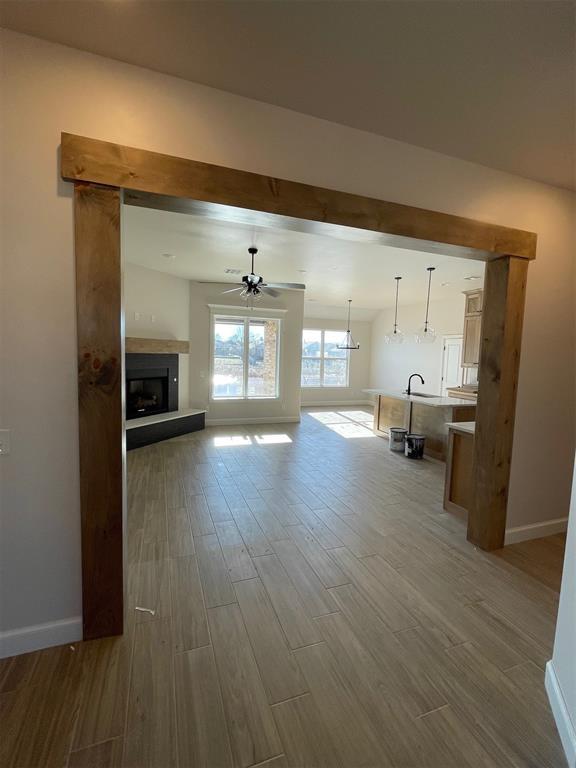 unfurnished living room with light wood-type flooring, ceiling fan, and sink