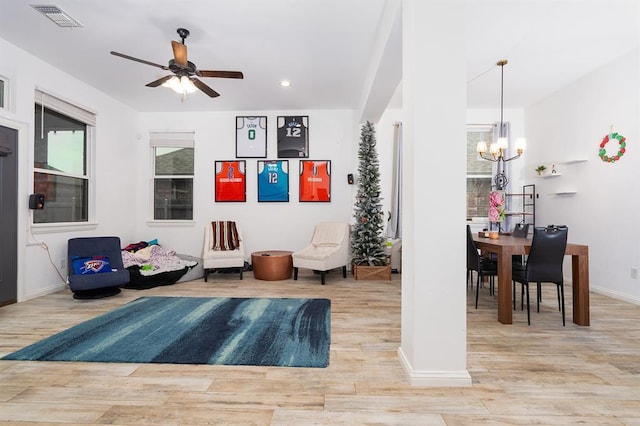 sitting room with ceiling fan with notable chandelier and light hardwood / wood-style flooring