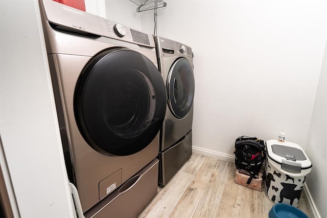 clothes washing area featuring washer and dryer and light wood-type flooring