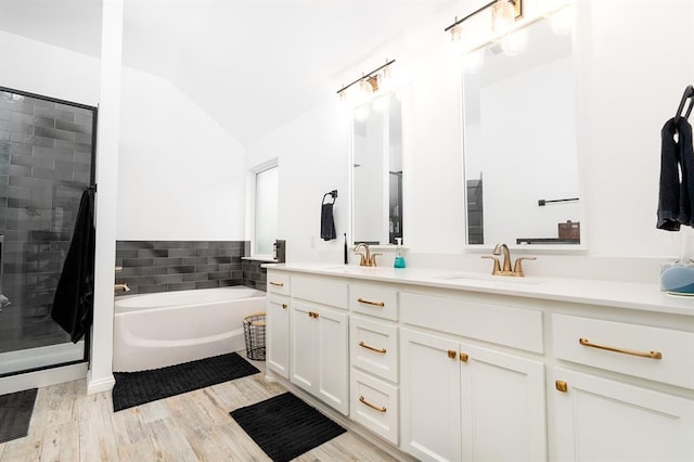 bathroom featuring vanity, wood-type flooring, vaulted ceiling, and shower with separate bathtub