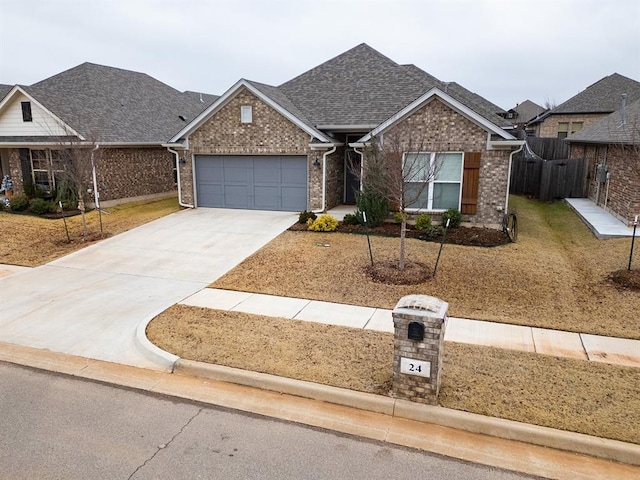 24 Carat Dr, Yukon, OK 73099 - view of front facade with brick siding, an attached garage, concrete driveway, and roof with shingles