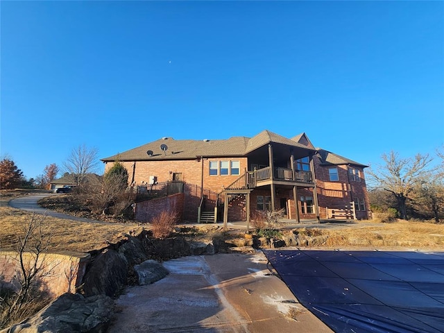 rear view of house with a patio, a balcony, and a covered pool